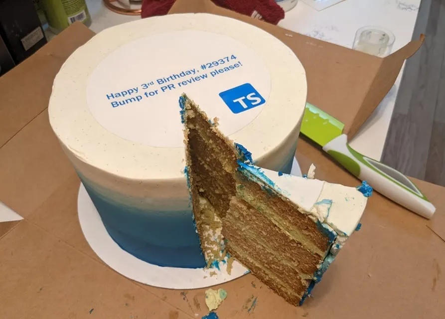 Fancy blue and white circular cake with text 'Happy 3rd Birthday, #293374' and 'Bump for PR review please!' above the TypeScript logo